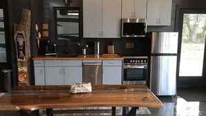 Een moderne keuken met grijze kastjes, roestvrijstalen apparatuur en een houten eettafel.