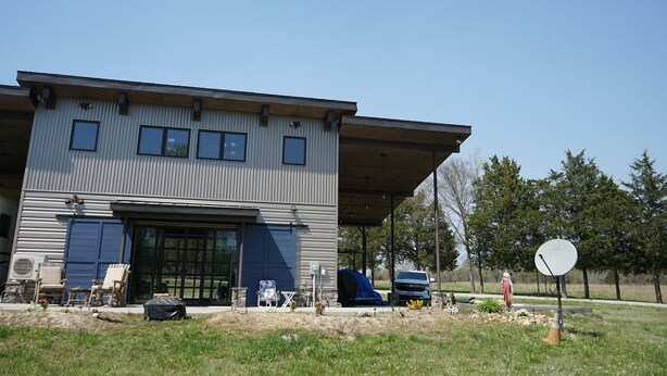 Een modern huis met twee verdiepingen, een garage, een overdekte veranda en een schotelantenne.