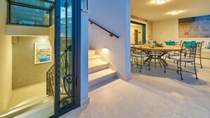 Un intérieur moderne avec un escalier, un coin repas comprenant une table ronde et des chaises, et une vue sur l’extérieur grâce à une porte vitrée.