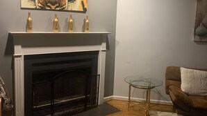 Un salon avec une cheminée, une table en verre, un canapé marron et un tableau représentant un tigre accroché au mur.