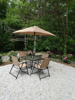 A round table with four chairs and a large umbrella in a garden setting. - Cedar Lodge, serene all wood escape in Blue Ridge (Newland)