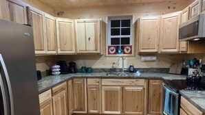 A kitchen with wooden cabinets, a stainless steel refrigerator, a sink, and a stove. - Cedar Lodge, serene all wood escape in Blue Ridge (Newland)