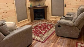 A cozy living room with a fireplace, a flat-screen TV mounted above it, and a large sectional sofa. - Cedar Lodge, serene all wood escape in Blue Ridge (Newland)