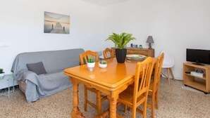 Ein gemütlicher Wohnraum mit Esstisch, Stühlen, einer Couch, einem Fernseher und einem Bild an der Wand.