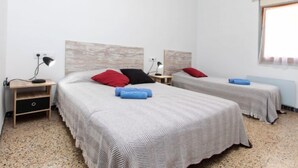 Ein Hotelzimmer mit zwei Betten, jeweils mit Kopfteil, Nachttischen und Lampen. Es gibt ein Fenster mit Vorhängen, und der Raum hat einen Teppichboden.