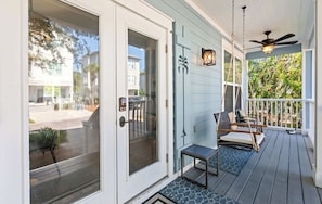 A porch with a ceiling fan, a swing chair, and a bench.