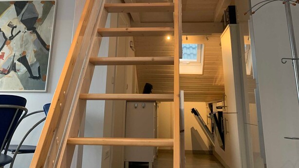 Un escalier en bois mène à une mezzanine d’où l’on peut admirer le ciel.