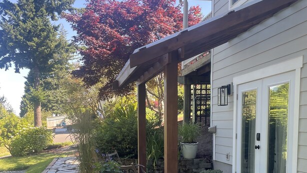 A covered patio area with a stone pathway leading to a house.