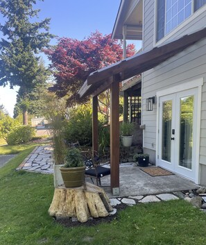 A covered patio area with a stone pathway leading to a house.