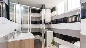 Une salle de bain moderne avec un lavabo blanc, un miroir et des toilettes. Les murs sont décorés de rayures noires et blanches, et on y trouve un meuble en bois.