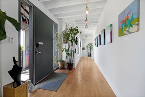 A hallway with wooden flooring, potted plants, and artwork on the walls.