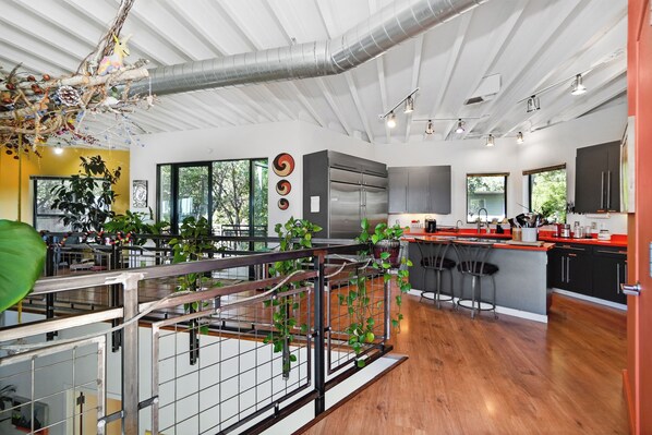 A modern kitchen with a central island, stainless steel appliances, and a view of the outdoors.