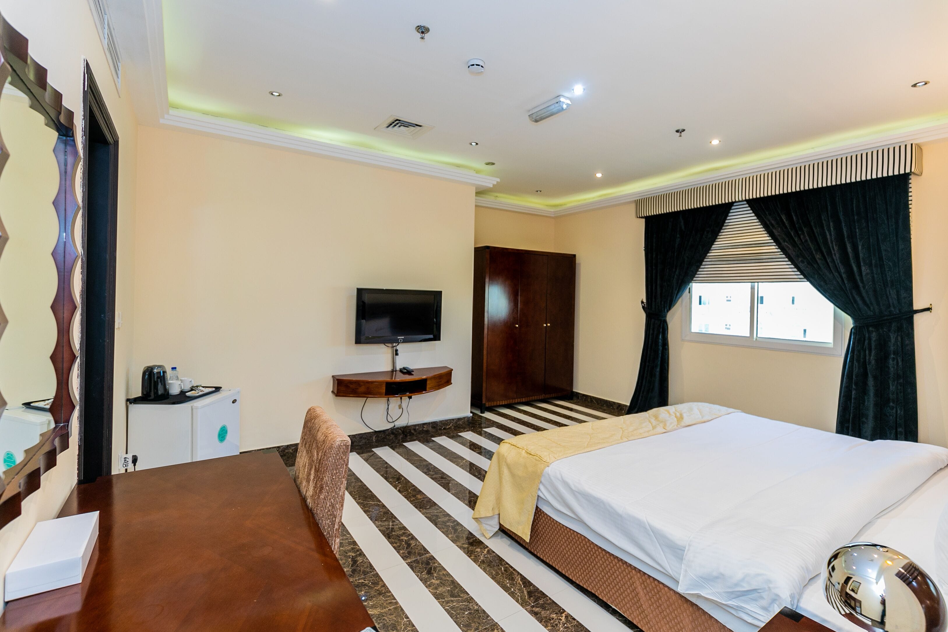 A hotel room with a bed, a TV, a desk, and a wardrobe.