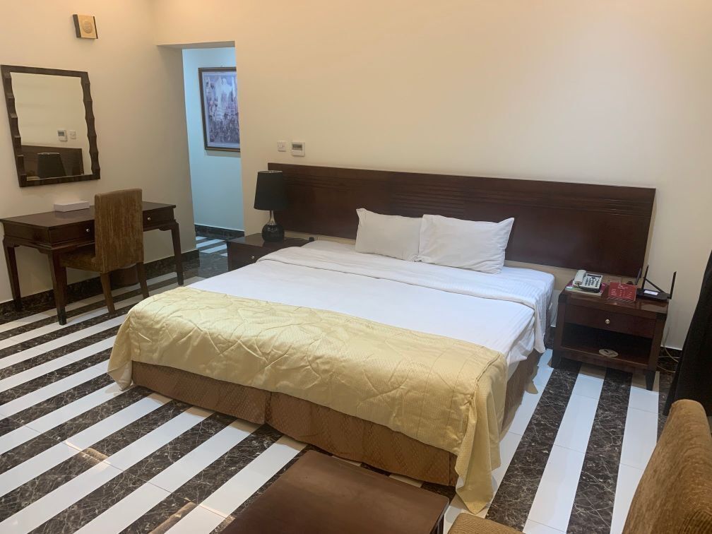 Una habitación de hotel con una cama grande, un escritorio, una silla, una mesita de noche y un teléfono.