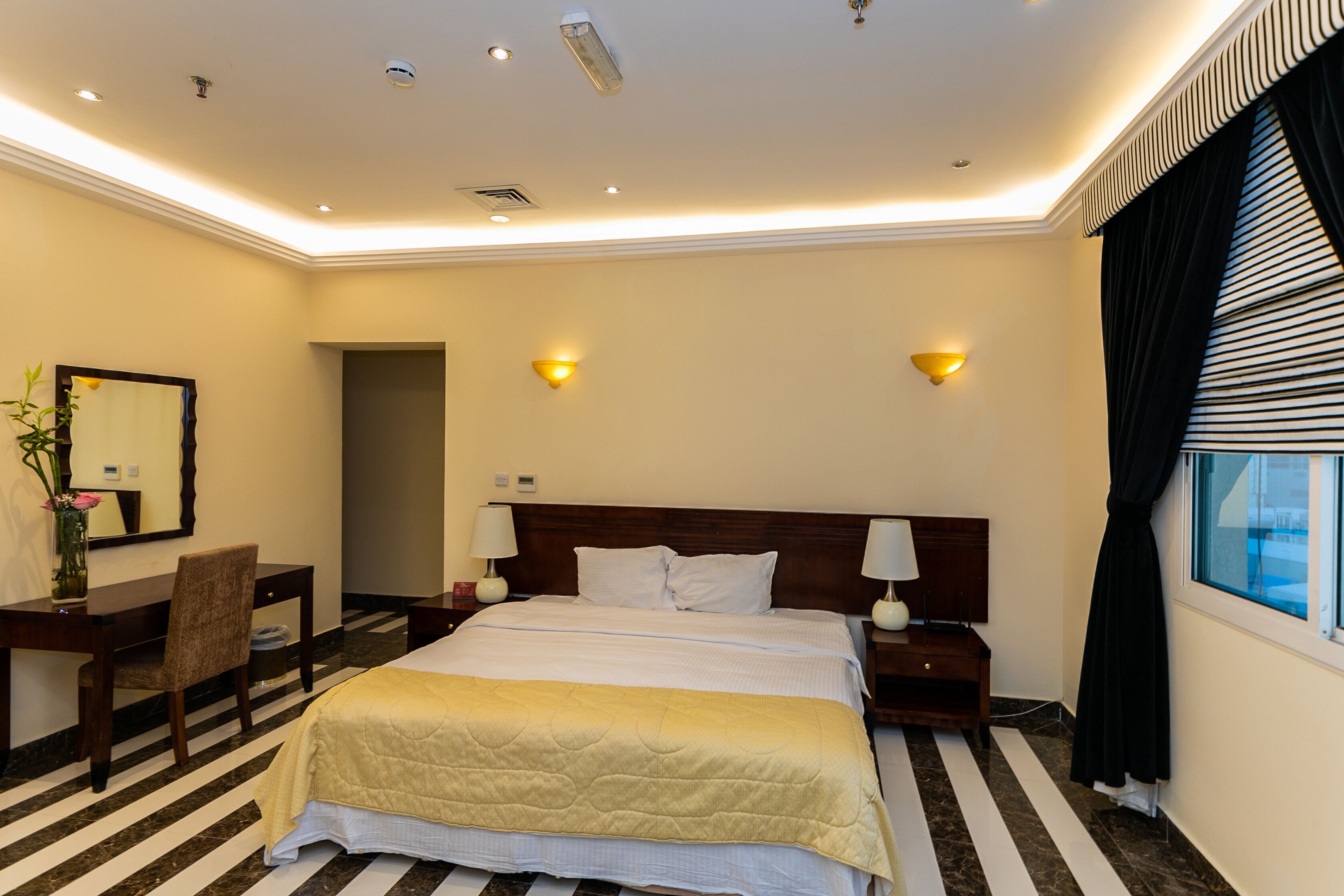 Een hotelkamer met een groot bed, nachtkastjes, een bureau en een stoel.