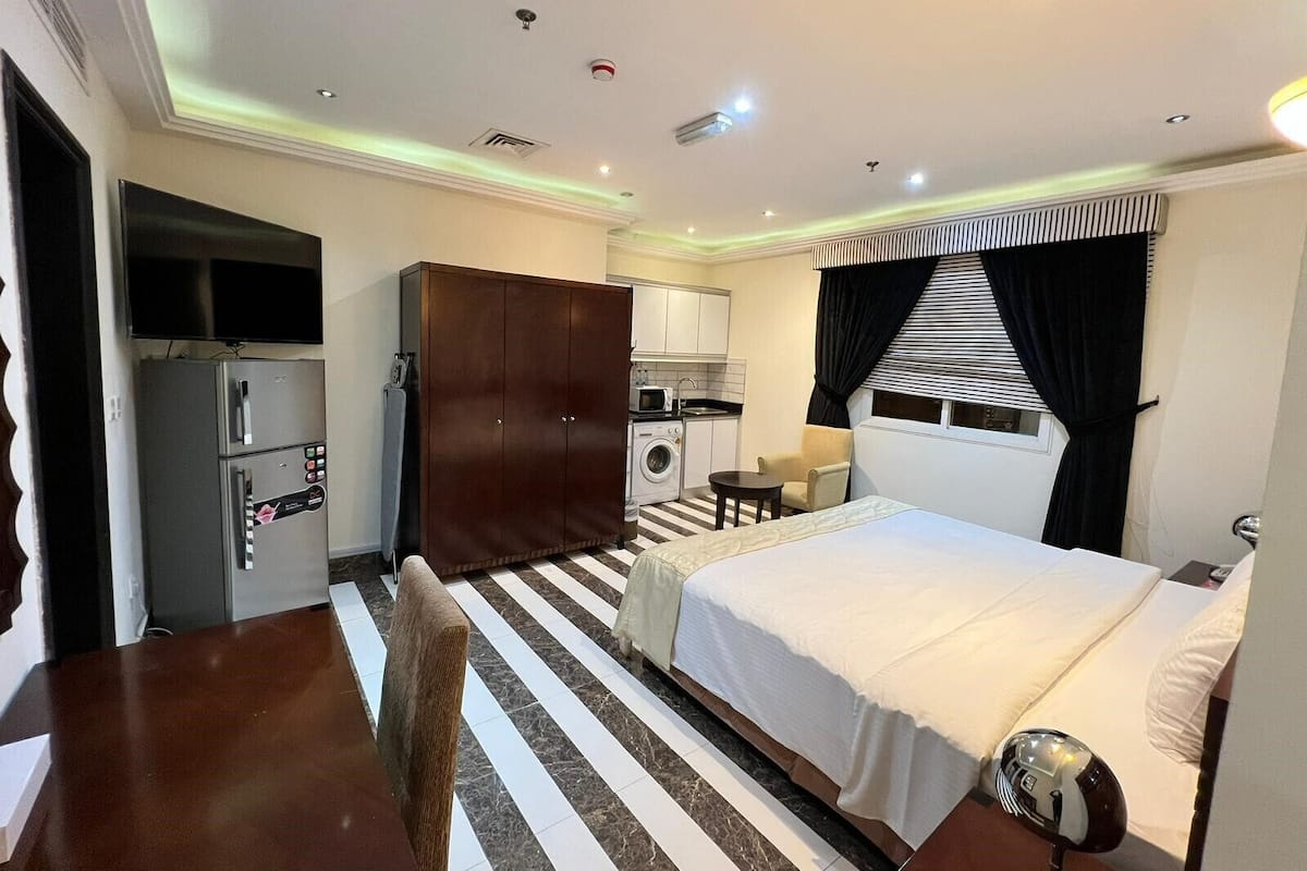 Une chambre d’hôtel comprenant un lit, un bureau, une armoire, une kitchenette et une salle de bain.