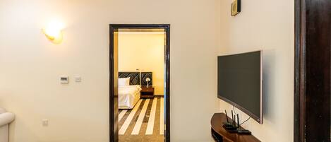 A hotel room with a bed, a TV, and a console table.