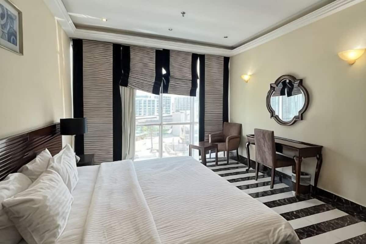 Habitación de hotel con una cama grande, un escritorio, una silla y vistas a la ciudad.