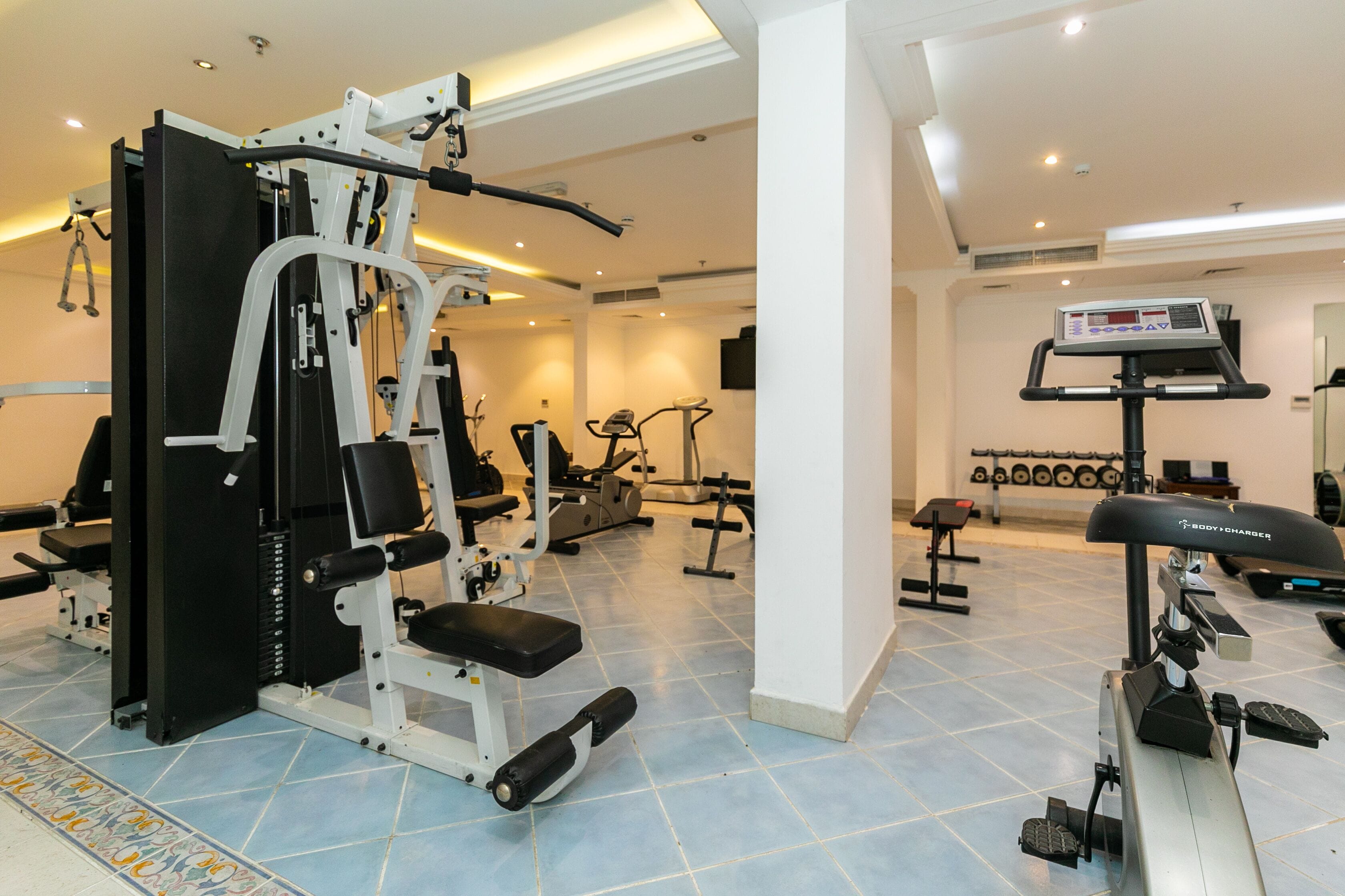 A gym with various exercise equipment, including a weight machine, treadmills, and dumbbells.