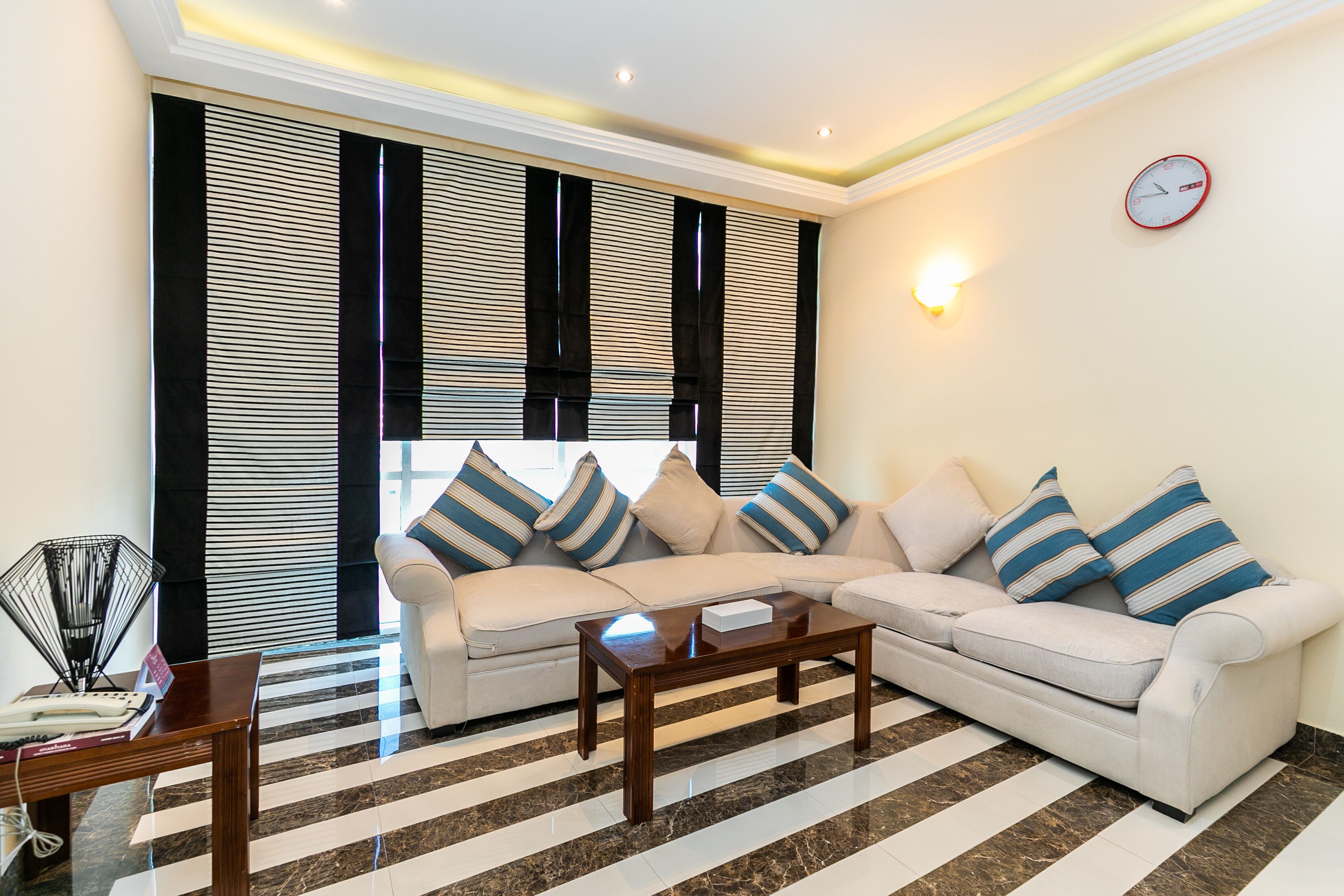 A living room with a sofa, a coffee table, and striped curtains.