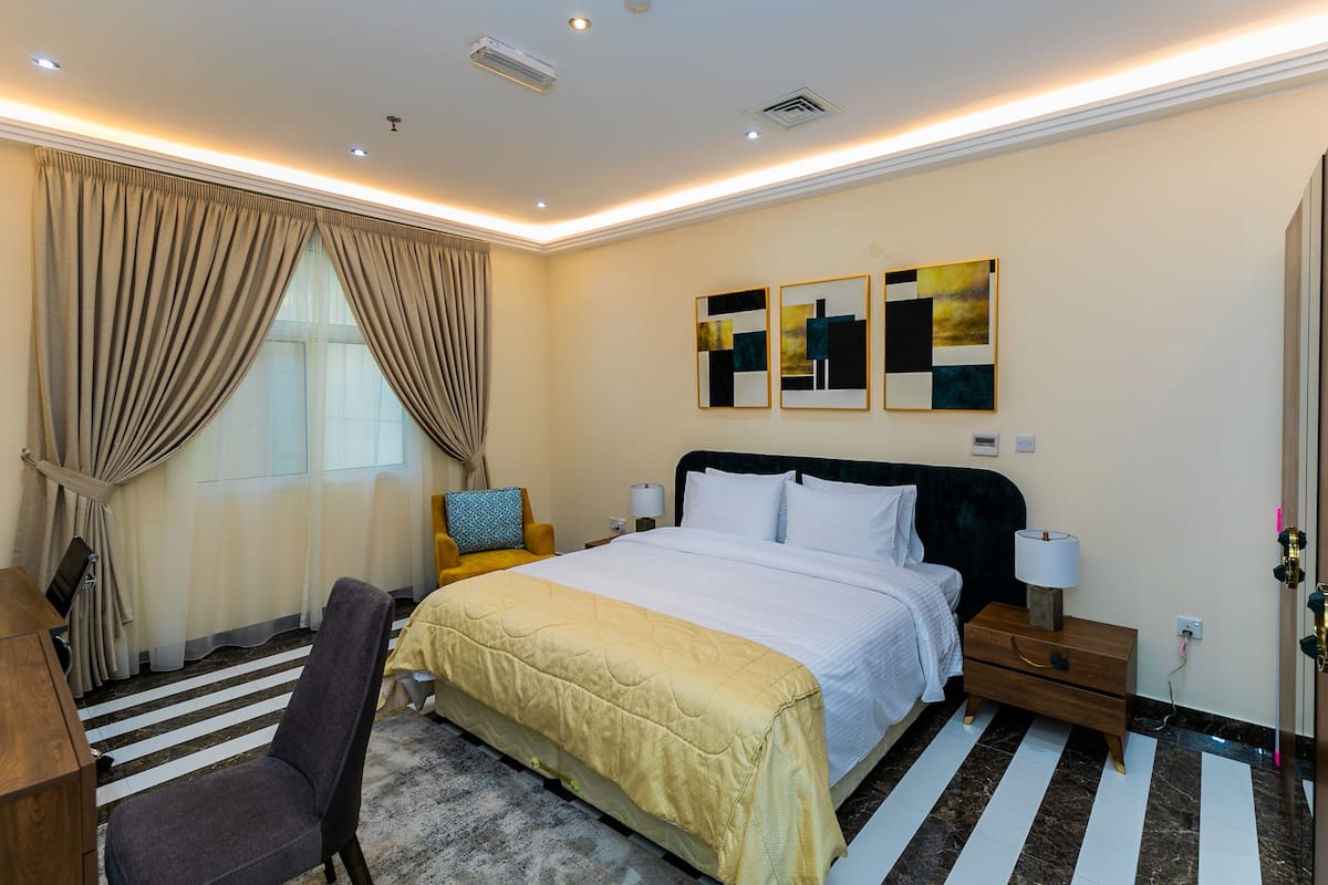Une chambre d’hôtel avec un grand lit, un bureau, une chaise et des œuvres d’art accrochées au mur.