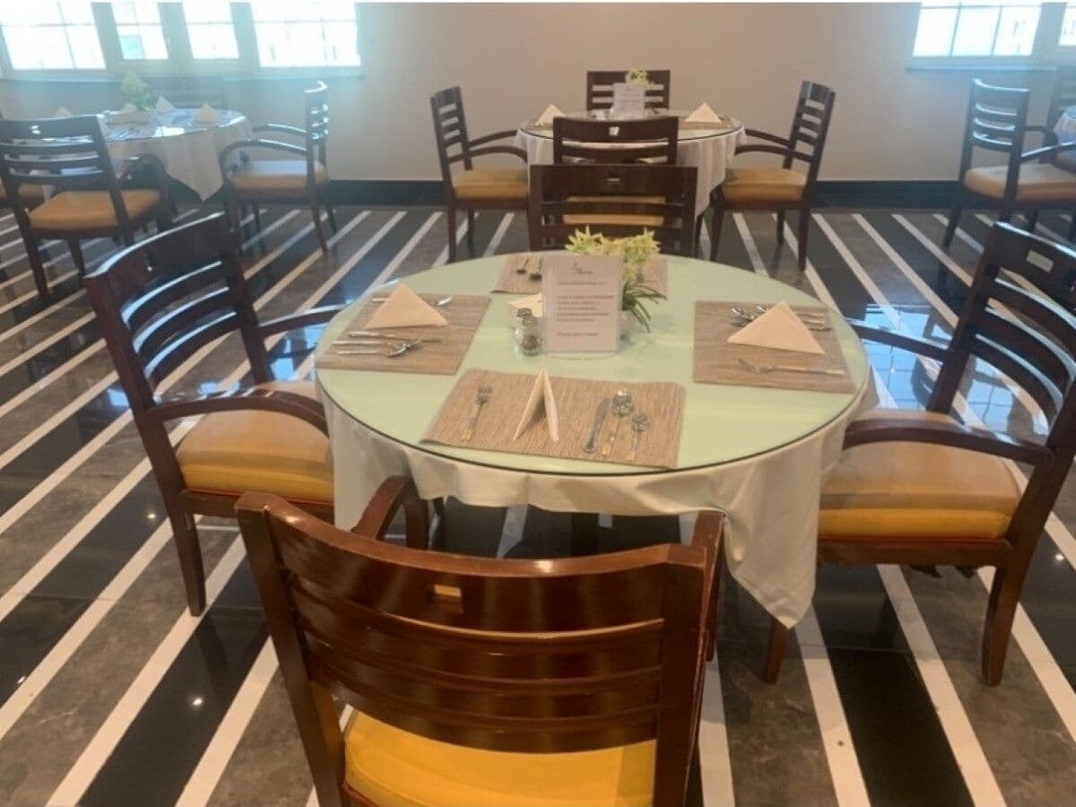 A dining area with round tables, wooden chairs, and a striped floor.