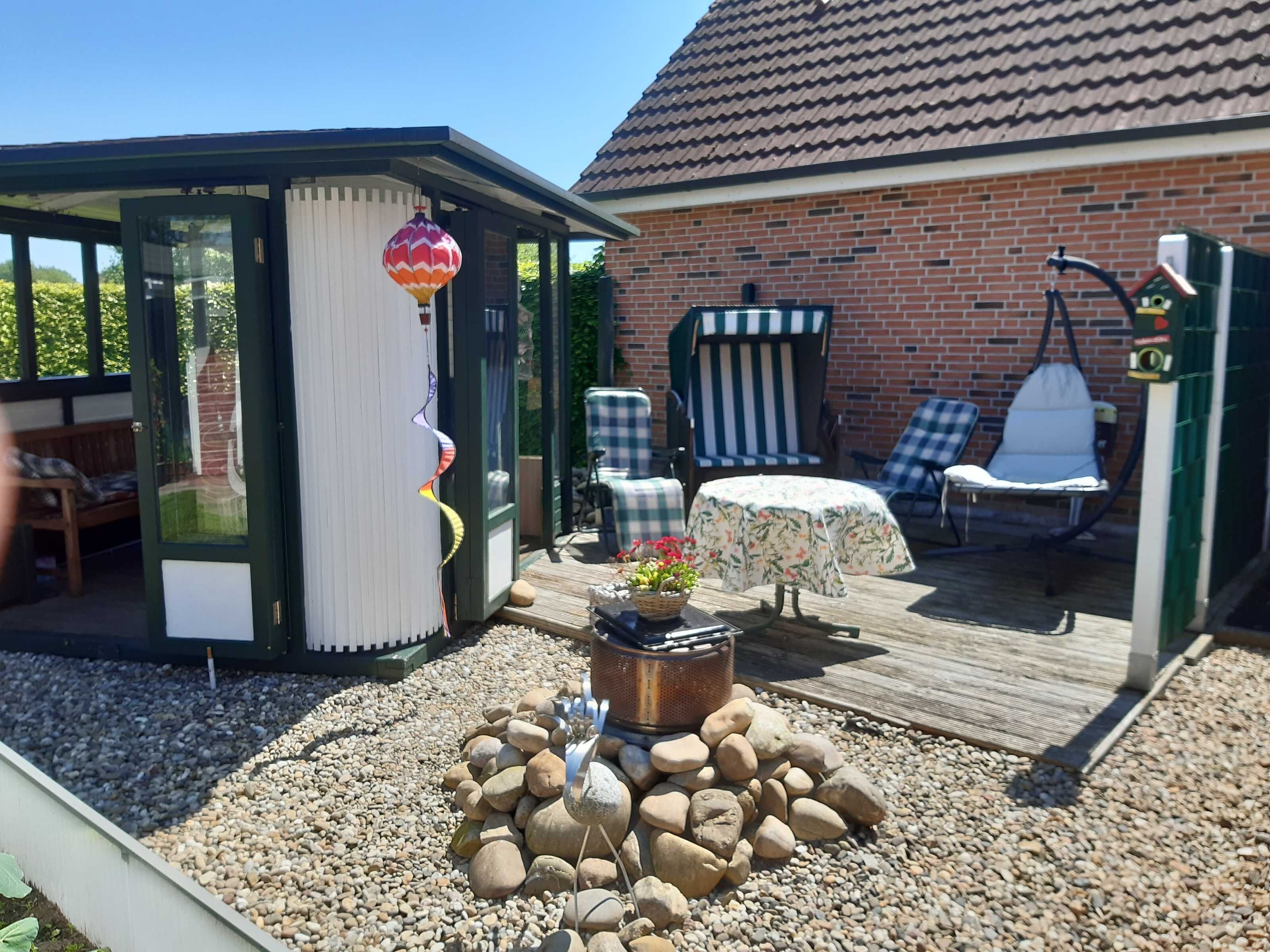 A covered outdoor seating area with a table and chairs, a hot air balloon decoration, and a small garden with rocks and a planter.