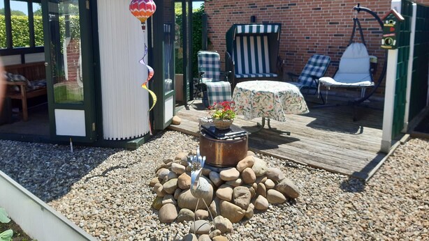 A covered outdoor seating area with a table and chairs, a hot air balloon decoration, and a small garden with rocks and a planter.