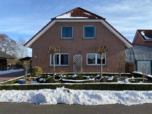 Een tweelaags bakstenen huis met een symmetrische gevel, een centrale ingang en een met sneeuw bedekte tuin.