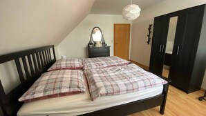A bedroom with a bed, a dresser, a mirror, and a wardrobe.
