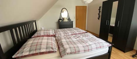 Un dormitorio con cama, cómoda, espejo y armario.