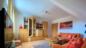 A living room with a sofa, a coffee table, a TV, and a wooden cabinet with glass doors.