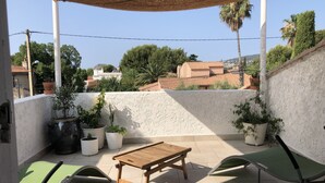 A patio with a wooden table and two green chairs, surrounded by potted plants and a white wall. - Villa 150 m2, 4 air-conditioned bedrooms 8/10pers swimming pool, close to beaches  (La Ciotat)