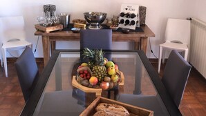 A dining area with a glass table, chairs, a fruit bowl, a bread tray, a wine rack, and a clock on the wall. - Villa 150 m2, 4 air-conditioned bedrooms 8/10pers swimming pool, close to beaches  (La Ciotat)