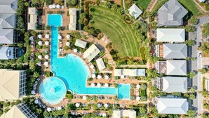 An aerial view of a resort with a large central pool, multiple guest villas, and well-maintained lawns. - Amour La Mer by AvantStay | Rooftop Patio, Pool Access, Walk to Beach (Seacrest)
