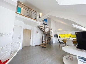 A modern apartment with a staircase, a dining area, and a kitchen. - Luxury duplex downtown with parking, close to port and beach (Granville)