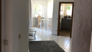 A hallway leading to a dining area with a table and chairs, a kitchen visible through an open door, and a grey rug on the floor. - Urlaub im Wunderschönen Hegau mit Alpenblick (Tengen)