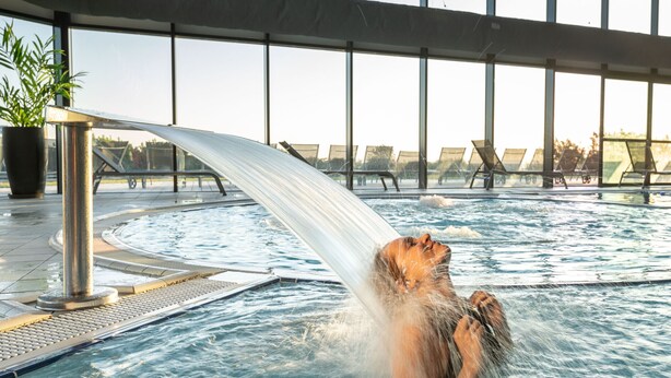 A person in a hot tub with a water feature.