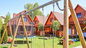 A playground with swings and a trampoline, surrounded by wooden houses with red roofs. - Awesome home in Bobolin with kitchen (Bobolin)