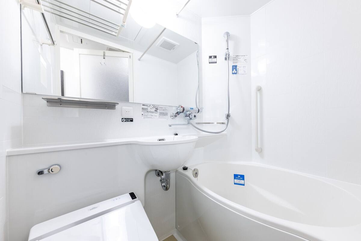 Un baño moderno con lavamanos, espejo y bañera blancos.