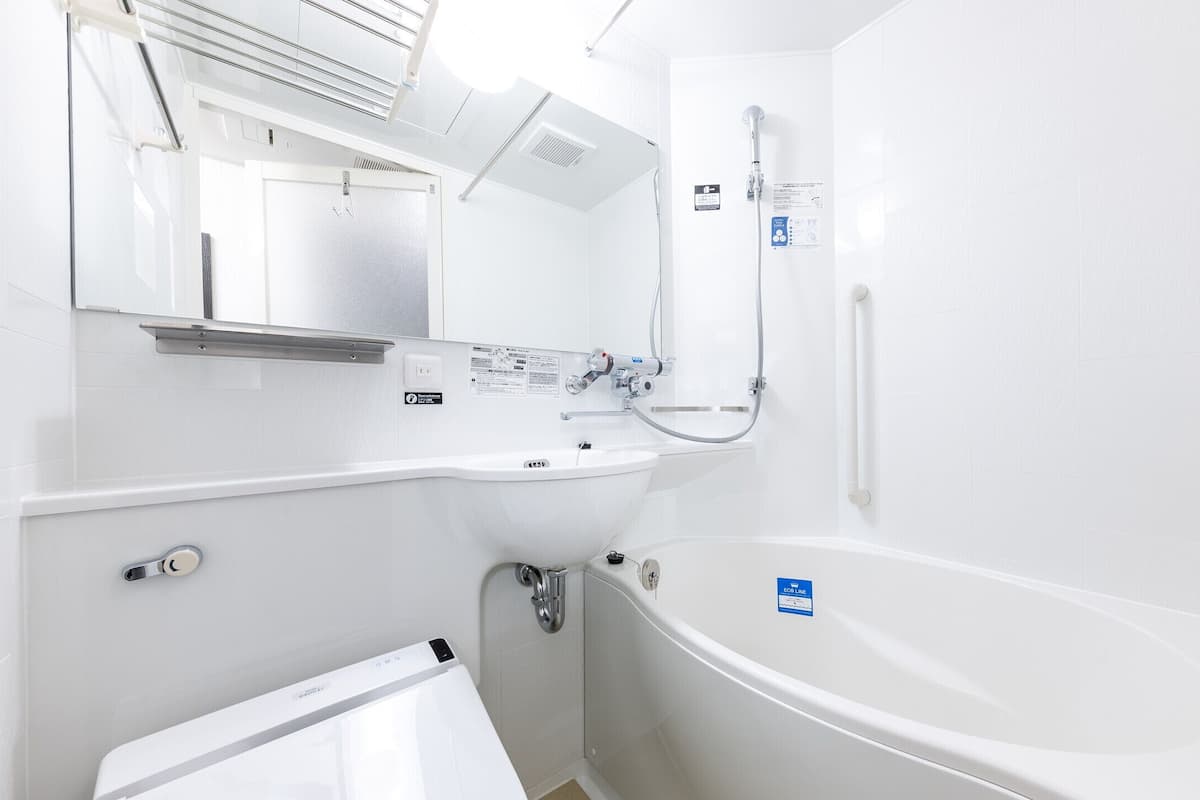 Un baño moderno con lavamanos, espejo y bañera blancos.