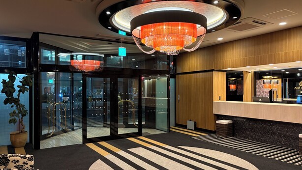 Een hotel lobby met een draaideur, een receptiebalie en een grote kroonluchter.