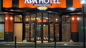 Het uiterlijk van APA Hotel, met een opvallende ingang en een draaideur.