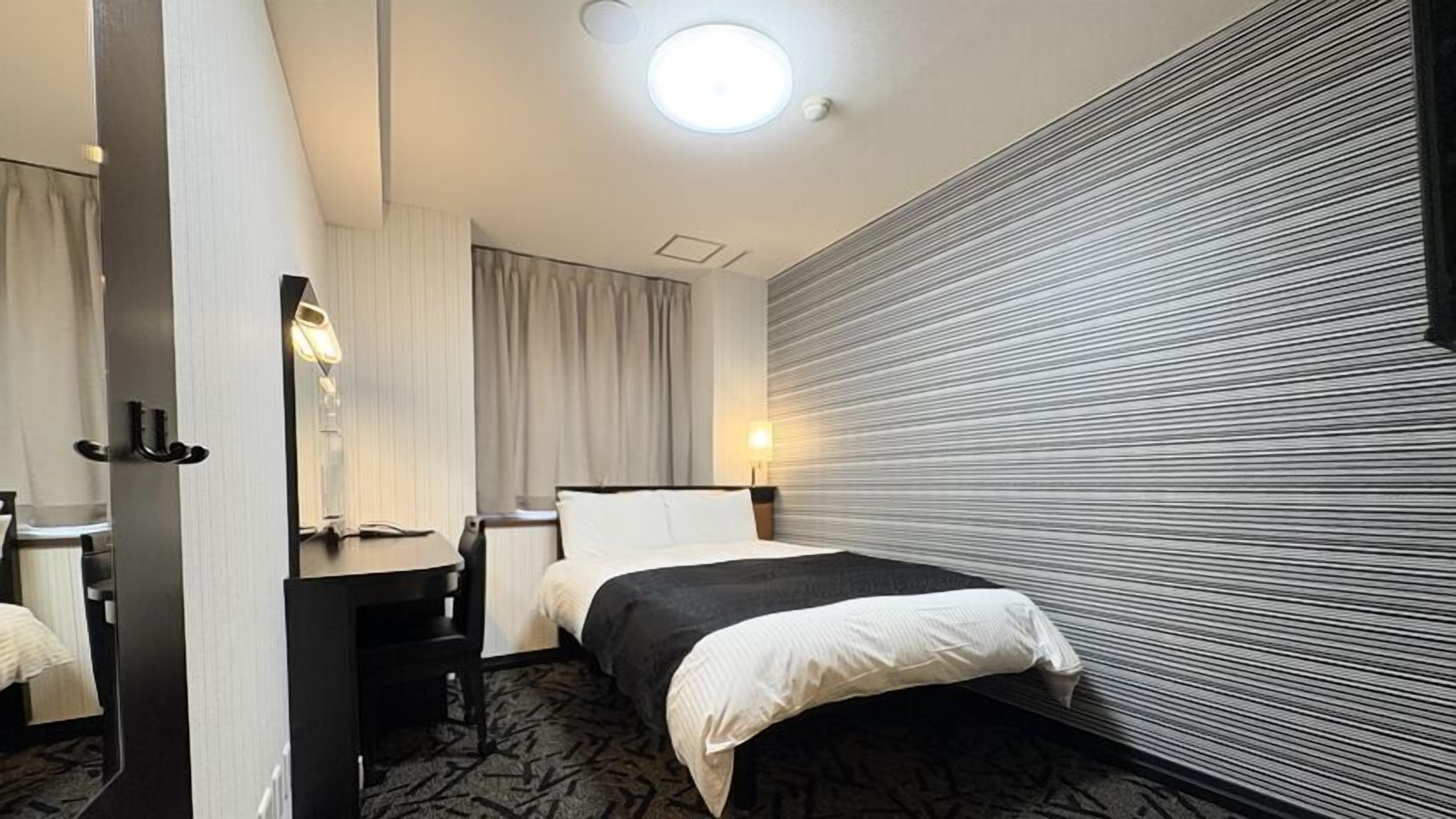 Een hotelkamer met een bed, een bureau, een spiegel en een wand met een structuur.