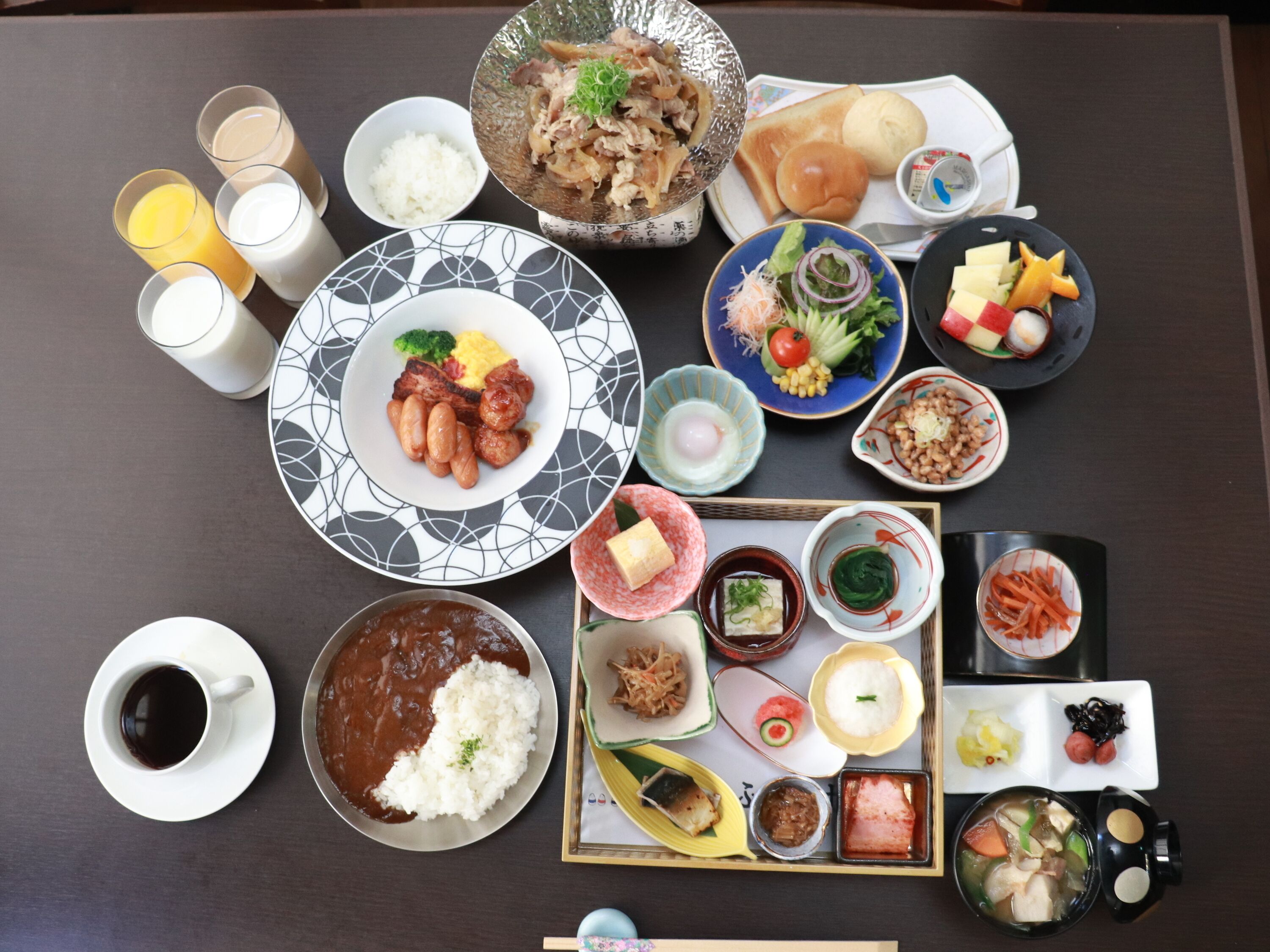 A variety of dishes and beverages on a table, including rice, meat, vegetables, and a cup of coffee.
