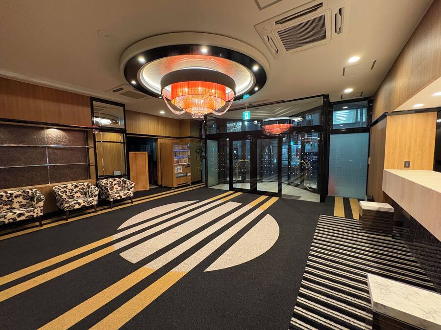 A hotel lobby with a reception desk, seating area, and a revolving door.