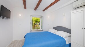 A bedroom with a bed, a window, a TV, and a wardrobe. - Apartment Bell (Dubrovnik)