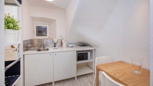 A compact kitchenette with a microwave, coffee maker, and toaster, a small window, and a white cabinet. - Apartment Bell (Dubrovnik)