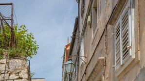A narrow stone staircase leading up to a building with a traditional facade, a metal gate, and a clear blue sky. - Apartment Bell (Dubrovnik)