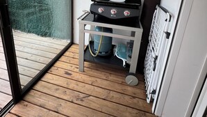 A small, enclosed patio area with a barbecue grill, a water heater, and a wall-mounted plant holder. - Petite Maison (Le Lavandou)
